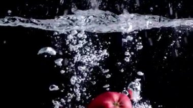 Kırmızı elmalar siyah arka planda suya düşer.