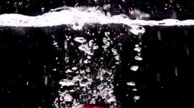 Kırmızı elmalar siyah arka planda suya düşer.