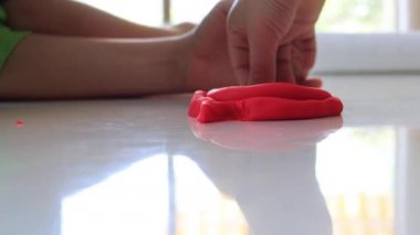 Childs 'ın elleri masada renkli kil oynuyor. Parmaklarının ve yaratıcılığının ve eğitiminin iyi motor becerilerinin geliştirilmesi