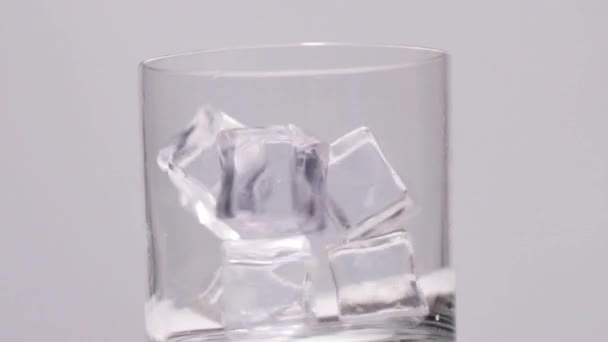 Häll vatten i glas med is på vit sten bakgrund — Stockvideo