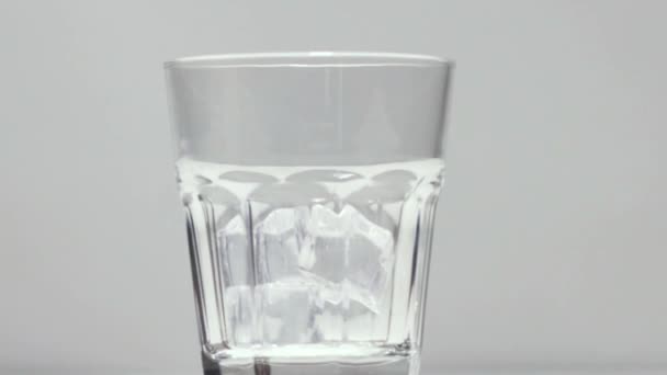 Whiskey in het glas gieten met ijs — Stockvideo