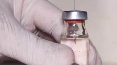 Şırınganın iğnesi cam şişeden ilaç alıyor.