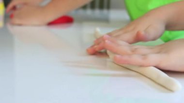 Childs 'ın elleri masada renkli kil oynuyor. Parmaklarının ve yaratıcılığının ve eğitiminin iyi motor becerilerinin geliştirilmesi