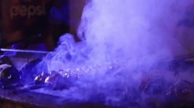 Etten yapılmış çok sayıda çiğ Türk şiş Adana kebabı ızgarada mangal kömürü üzerine dizilmiştir..