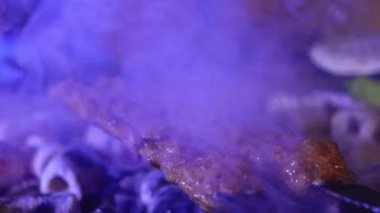 Etten yapılmış çok sayıda çiğ Türk şiş Adana kebabı ızgarada mangal kömürü üzerine dizilmiştir..