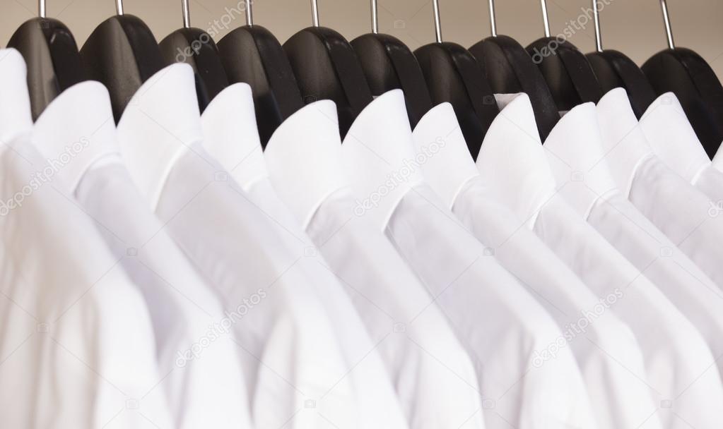 Row of cloth hangers with white shirts Stock Photo by ©senkaya 63806439
