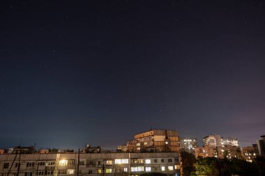 Bir sürü yıldız ve takımyıldızlı gece yıldızlı şehir manzarası. Yüksek binanın çatısından görüntüle.