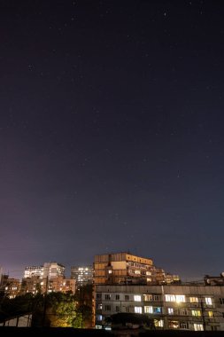Bir sürü yıldız ve takımyıldızlı gece yıldızlı şehir manzarası. Yüksek binanın çatısından görüntüle.