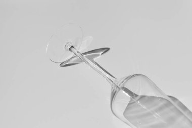 Beyaz yüzeyde şampanya kadehi. Beyaz masadaki gölgeli cam..