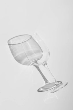 Şarap kadehi beyaz arka planda yatıyor. Tek renkli sert gölgeli cam.