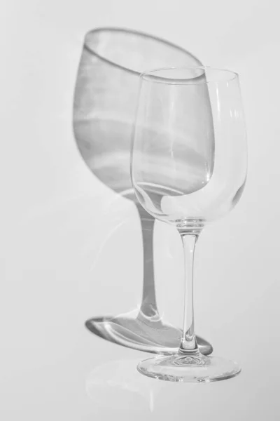 Wijnglas ligt op een witte achtergrond. Glas met harde schaduw in monochroom — Stockfoto