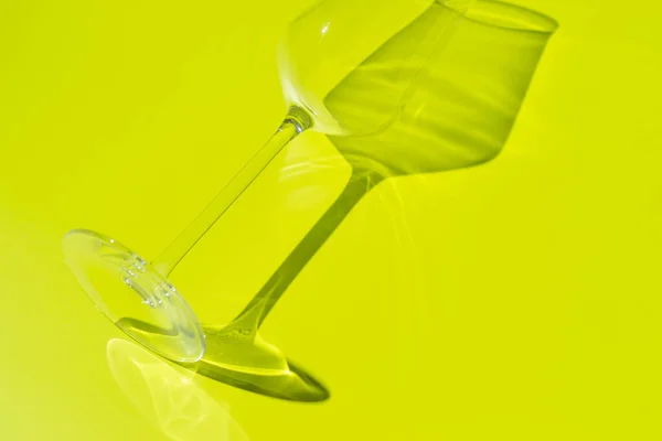 Uma parte da taça de champanhe fica na superfície verde clara. Vidro com sombra dura — Fotografia de Stock