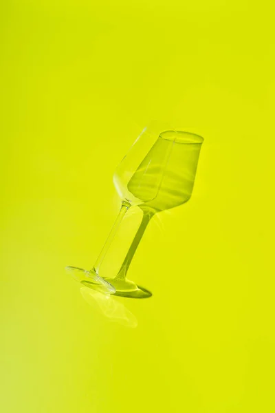 Champagnerglas liegt auf zitronengrüner Oberfläche. Glas mit hartem Schatten — Stockfoto