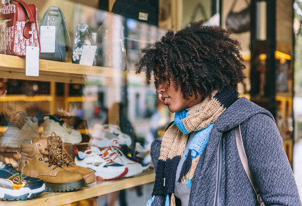 Привлекательная стильная афро-парикмахерша смотрит на витрину магазина в торговый день