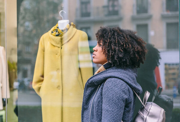 Привлекательная женщина с афро-волосами с пальто прогулки перед магазином стильной одежды