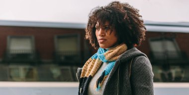 Afro saçlı esmer kadın. Sokakta özümsenmiş bakışlar.