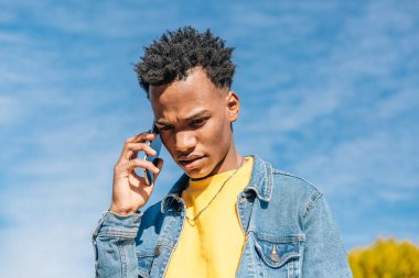 Endişeli genç adam bir yaz günü cep telefonuyla konuşur.