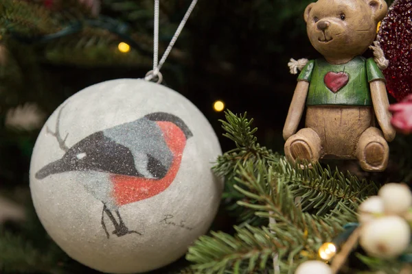 Christmas toy with a picture of bird on it on the christmas tree — Stock Photo, Image