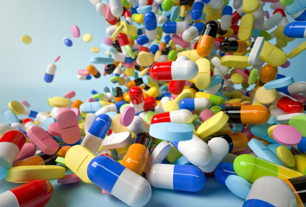 Many colorful pills and capsules falling on white background