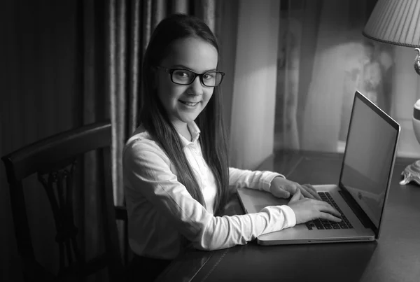 Black and white portrait of smiling schoolgirl using laptop — Stock Photo, Image