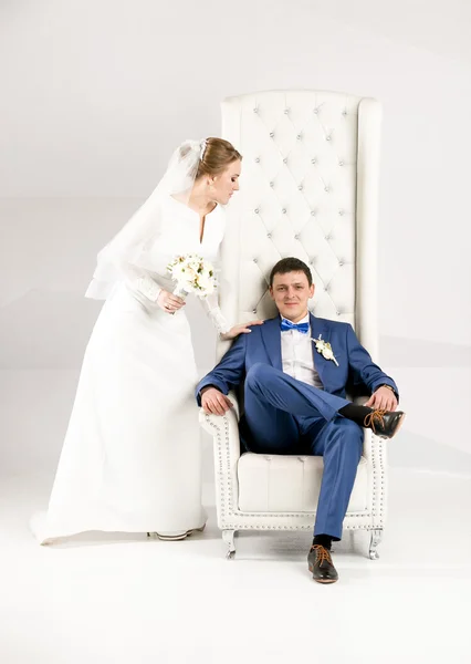 Retrato de noiva elegante abraçando o noivo sentado na cadeira — Fotografia de Stock