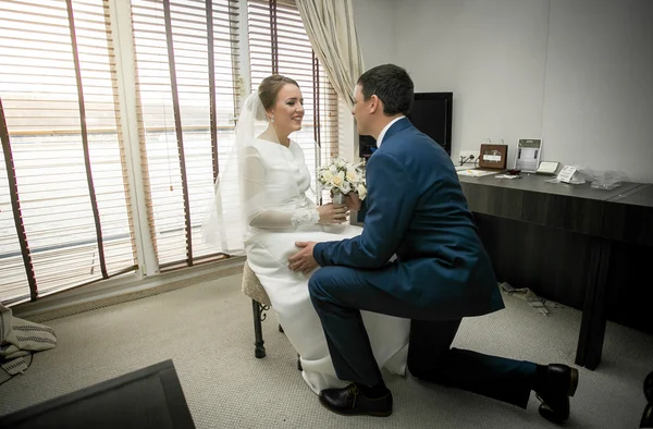 Handsome groom kneeling in front of bride sitting at hotel — Stock Photo, Image