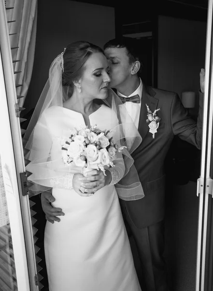 Black and white portrait of bride and groom kissing at hotel roo — Stock Photo, Image