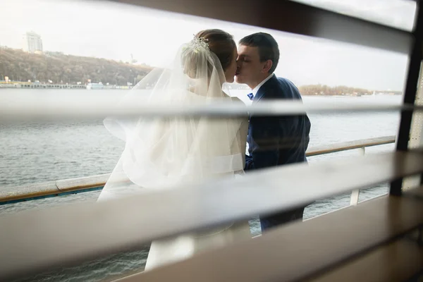 Portrait through jalousie of kissing happy newly married couple — Stock Photo, Image