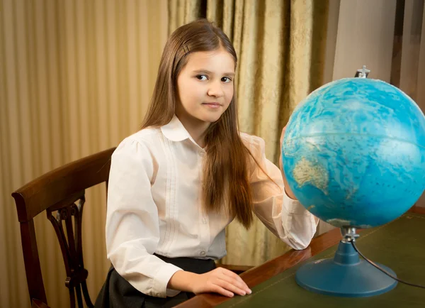 Beautiful schoolgirl posing at cabinet with Earth globe — Stock Photo, Image