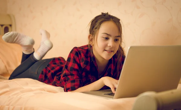 Retrato de una adolescente acostada en la cama y usando una computadora portátil — Foto de Stock