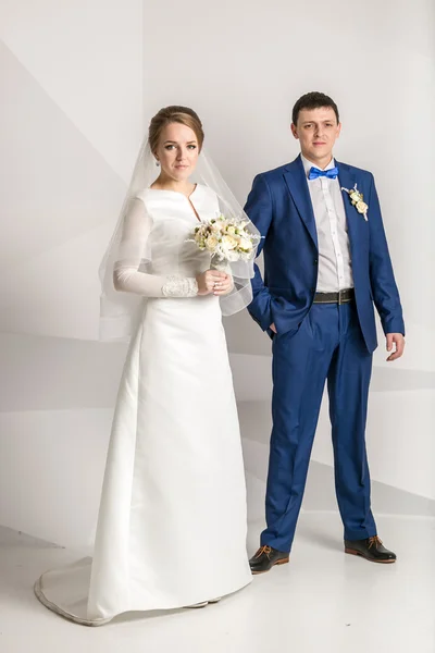 Frisch verheiratetes Paar posiert im Studio vor weißem Hintergrund — Stockfoto