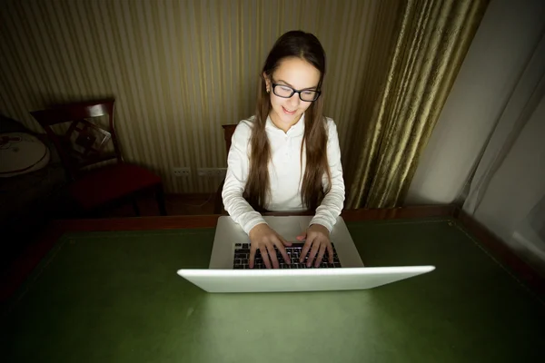 Menina sorridente em óculos usando laptop no final da noite — Fotografia de Stock