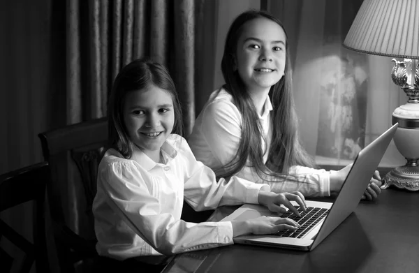 Retrato preto e branco de duas irmãs usando laptop — Fotografia de Stock