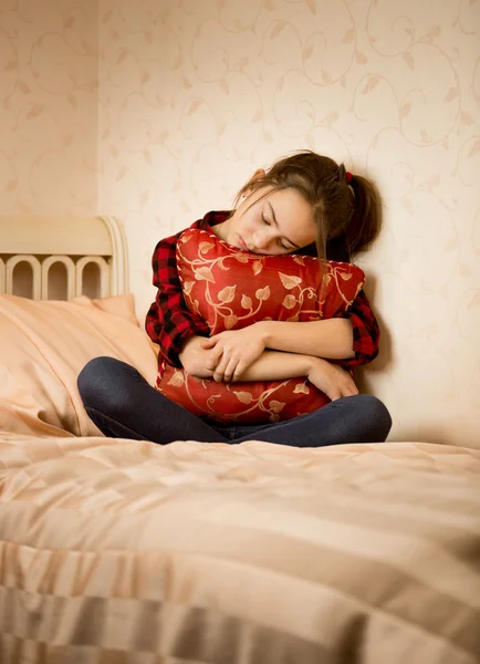 Depressief meisje zittend op bed en kussen omhelzen — Stockfoto