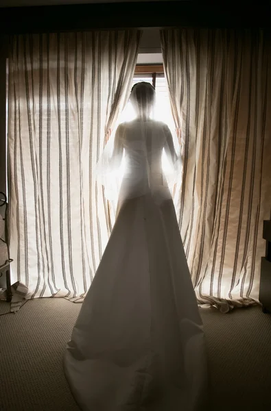 Getönte Aufnahme einer eleganten Braut, die aus dem Fenster auf das Hotel blickt — Stockfoto