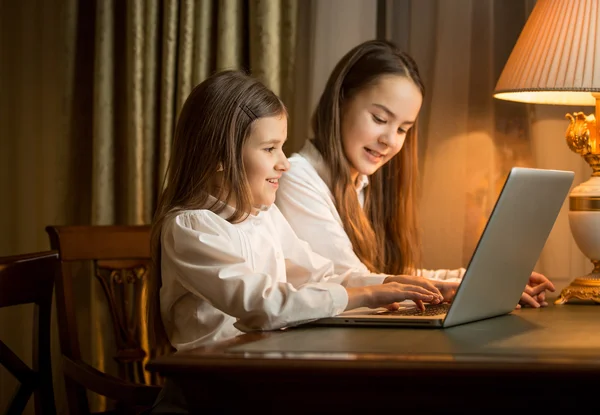 Two girls sitting at table and using laptop — Stock Photo, Image