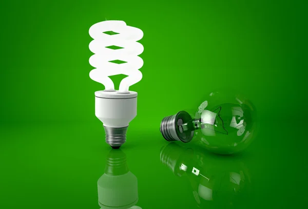 Светящаяся энергосберегающая лампочка и темная лампочка накаливания над зеленым — стоковое фото