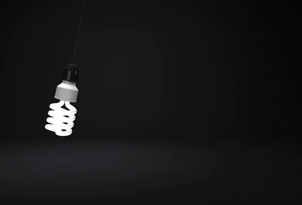 Bulbo de poupança de energia pendurado no fio no quarto escuro — Fotografia de Stock
