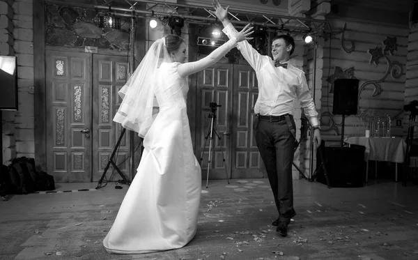 Black and white shot of bride and groom dancing at hall — Stock Photo, Image
