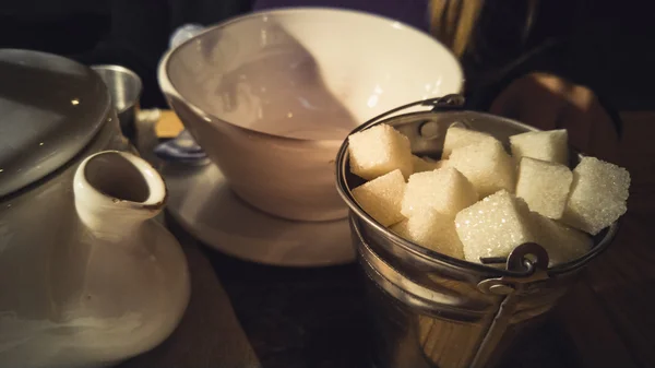 Getöntes Bild von Zucker, Tasse und Teekanne auf dem Tisch im Café — Stockfoto