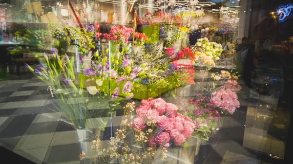 Toned shot of stands with flowers through store window — Stock Photo, Image