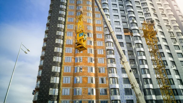 Industrial crane descend building crane cabin at building site — Stock Photo, Image