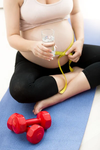 Gravid kvinna mäta magen med måttband på fitness ma — Stockfoto