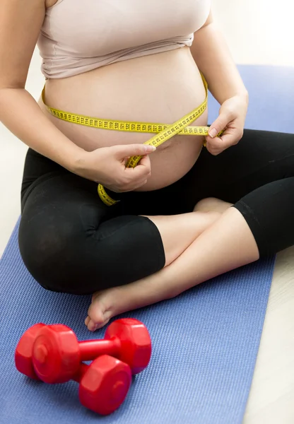 Closeup of pregnant woman measuring belly with tape — Stock Photo, Image