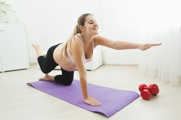 Feliz madre embarazada haciendo ejercicio y estiramiento en la esterilla de fitness —  Fotos de Stock