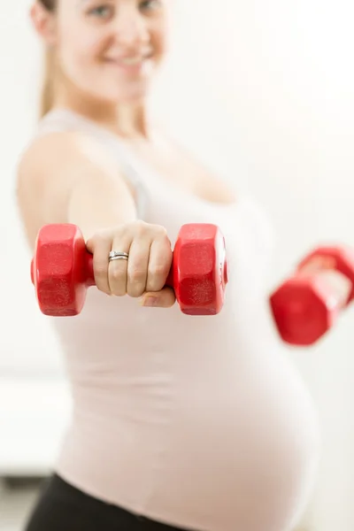 赤のバーベルを持っている妊娠中の女性の手のクローズ アップ — ストック写真