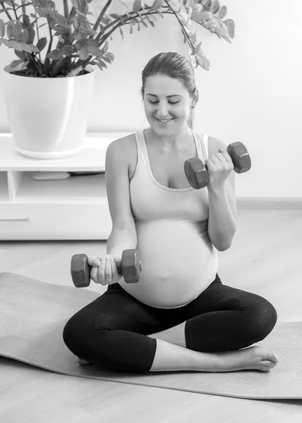 Zwart-wit schot van zwangere vrouw trainen met halters — Stockfoto