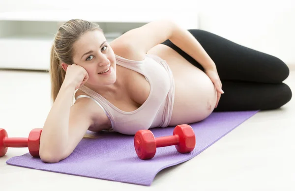 Lachende zwangere vrouw ontspannen na de uitoefening op fitness mat — Stockfoto