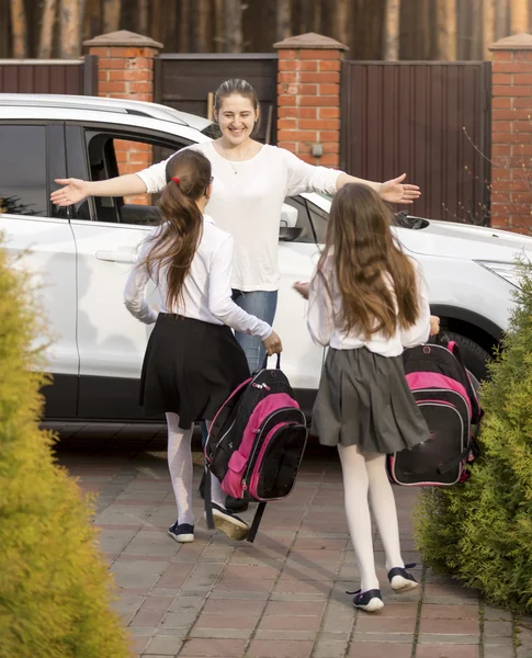 Весёлые школьницы бегут к маме, встречая их после школы. — стоковое фото