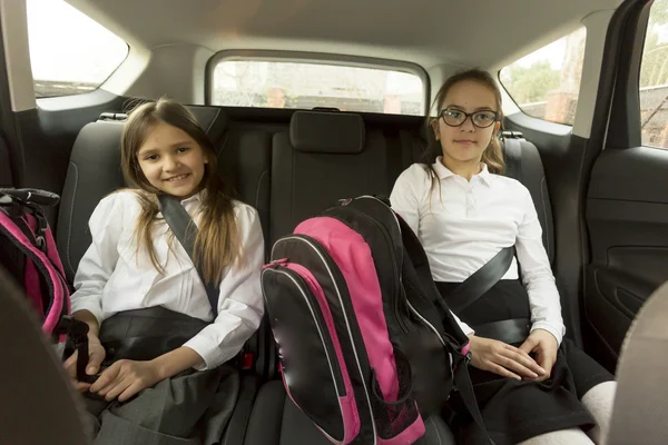 Portret van vrolijke schoolmeisjes zittend op de achterbank van de auto — Stockfoto